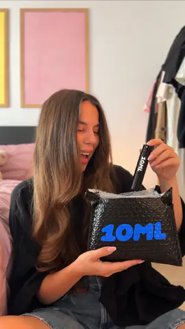 A smiling woman pulling a black 10ML atomiser out of its 10ML mailer